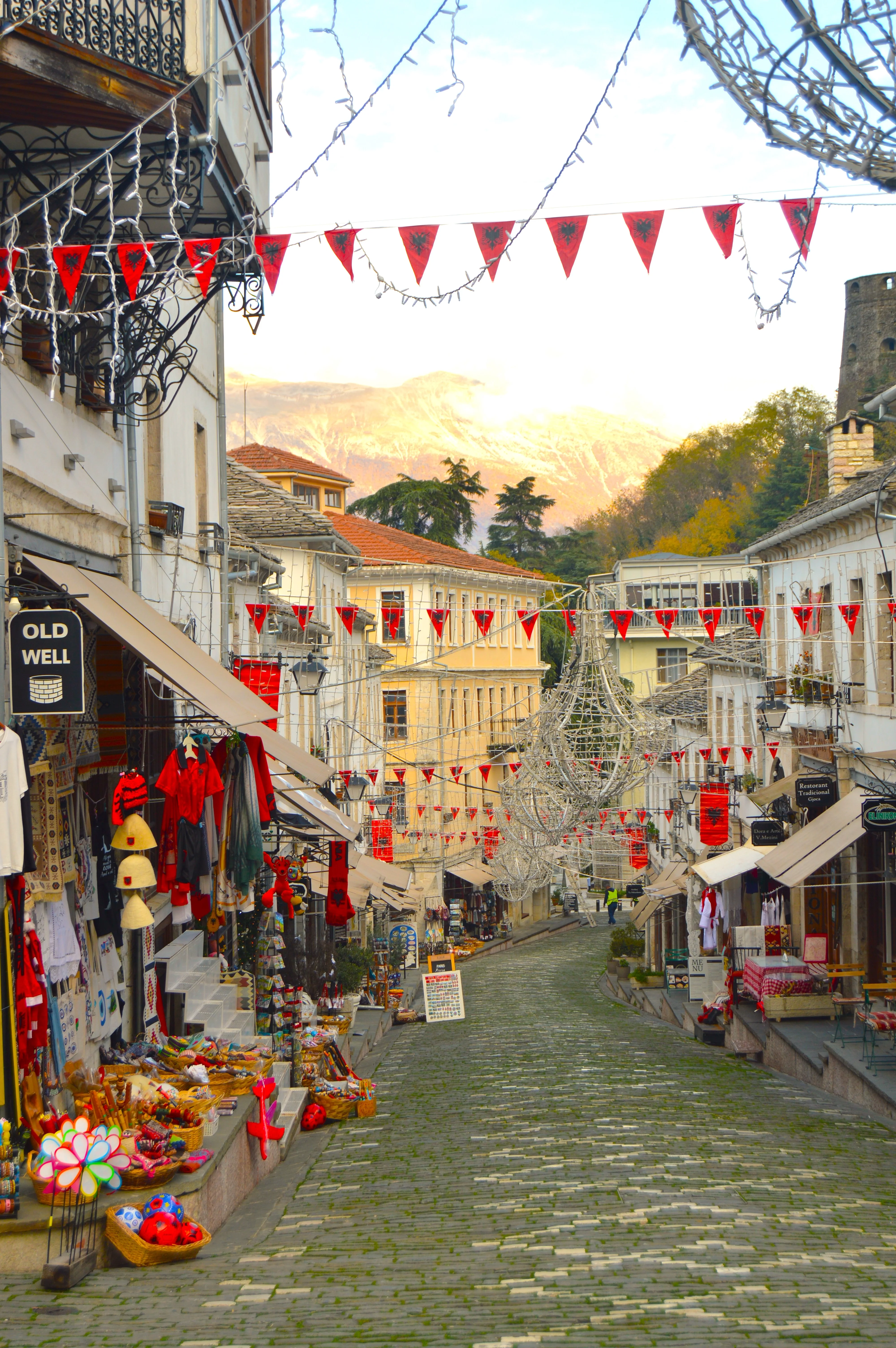Calle empedrada en Gjirokastër con tiendas artesanales y casas blancas