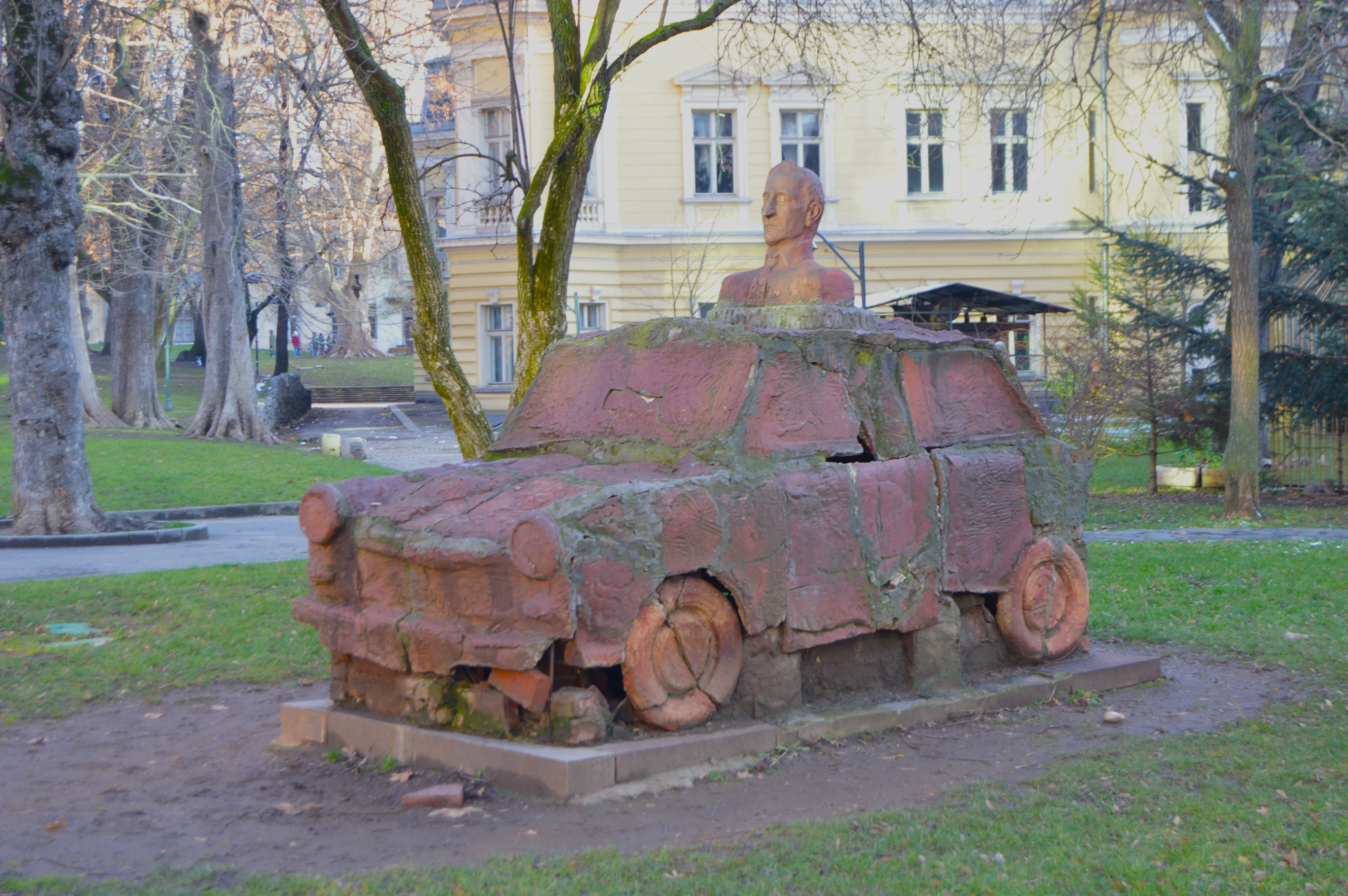Escultura urbana en Sofía: Fiat 128 estilizado de la URSS con figura emergiendo del techo