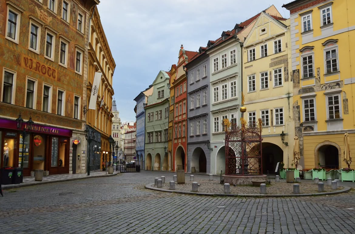 Calle adoquinada en el centro histórico de Praga, con edificios de arquitectura clásica de colores variados y vibrantes.