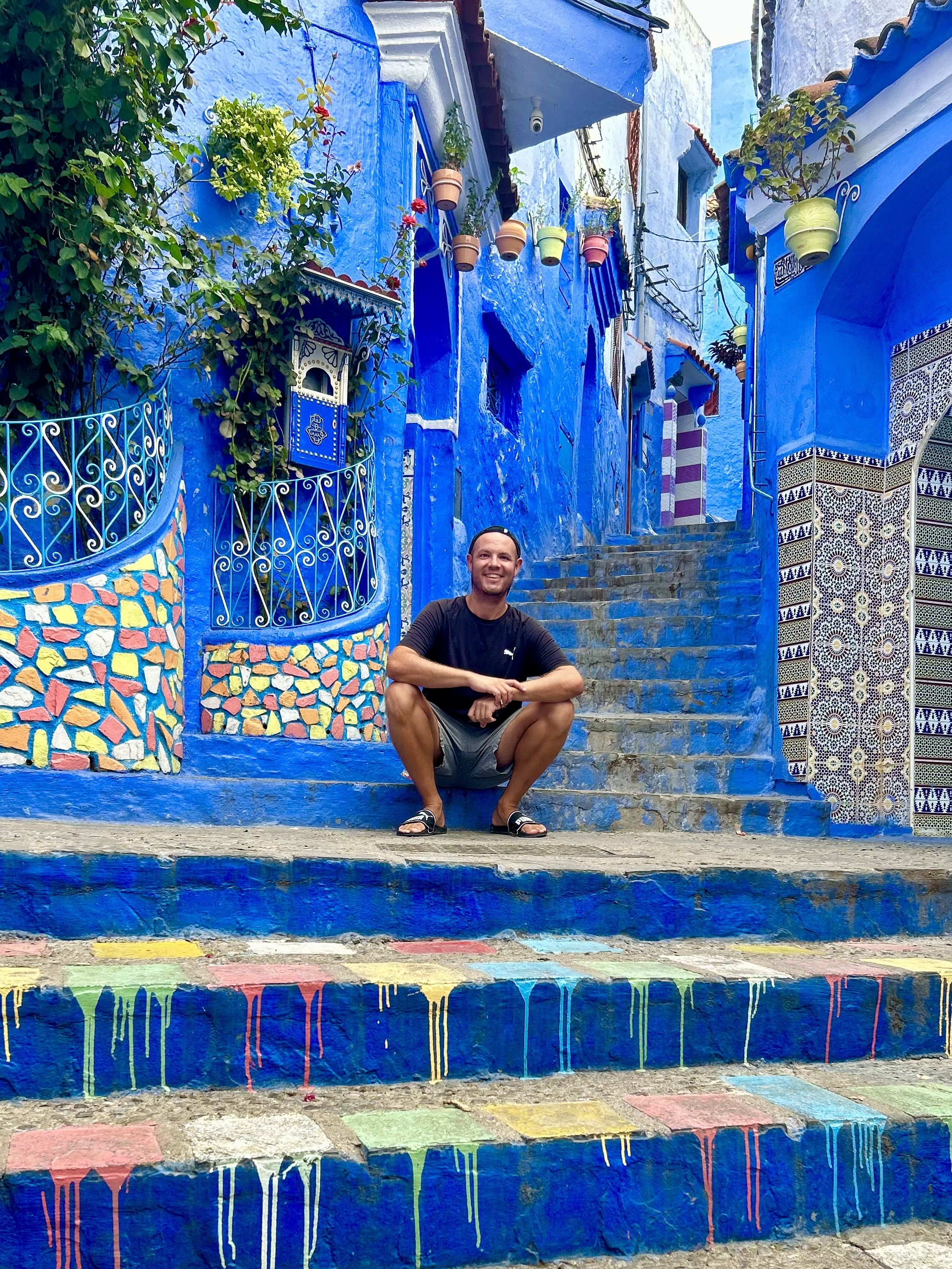 Viajero sentado en una calle azul de Chefchaouen, Marruecos